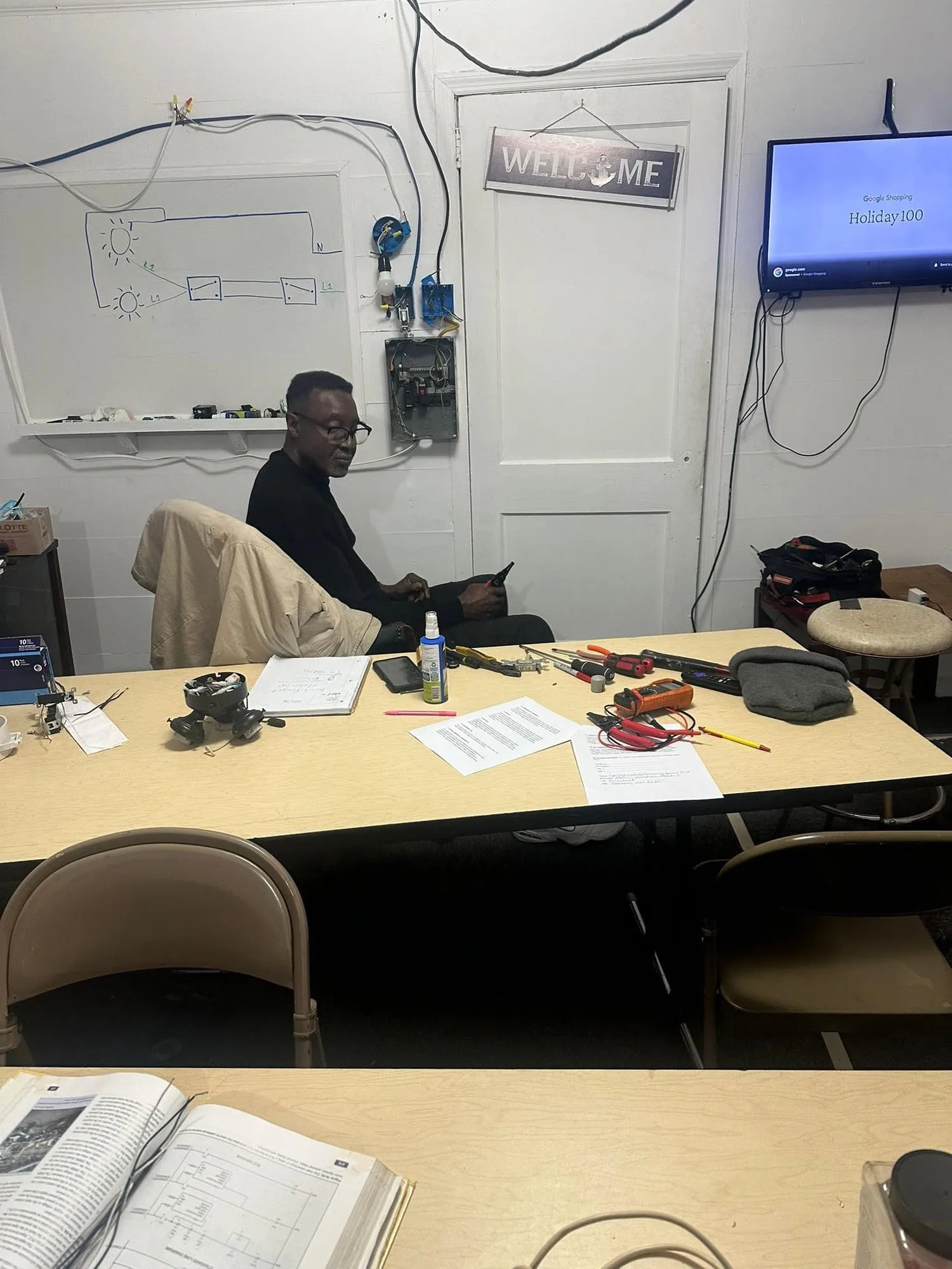 Practical electrical trade student wiring breaker boxes and testing circuits on training panels